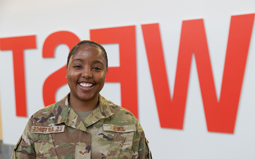 Student in Air Force uniform in front of "WEST" sign in Campus Center