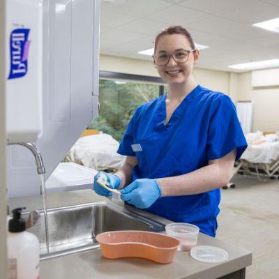 cna student brushing teeth in clinical lab