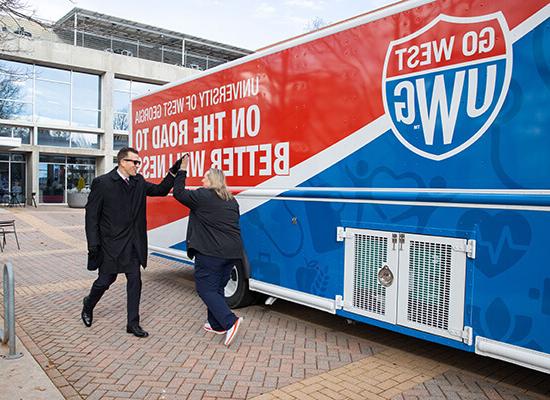 在线博彩 President Brendan Kelly high fives Chief Wellness Officer Bridgette Stewart in front of 在线博彩's mobile health unit.